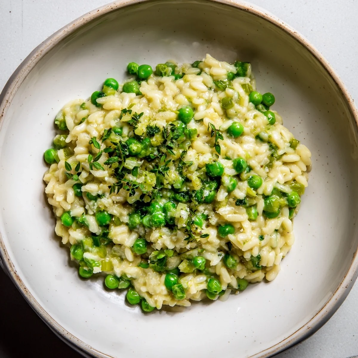 Bright and creamy Creamy Parmesan Orzo with Green Peas, garnished with fresh parsley, ready to eat.