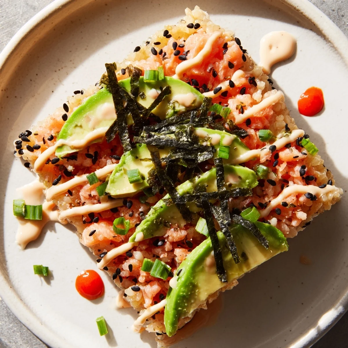 Golden-brown, crispy rice salmon stack topped with creamy avocado and spicy mayo for a delicious appetizer.