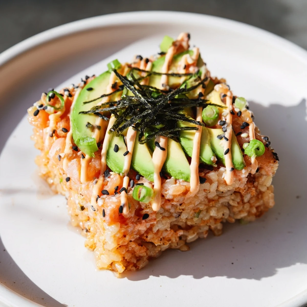 A close-up of a flavorful crispy rice salmon stack showing off fresh salmon and sesame seeds.