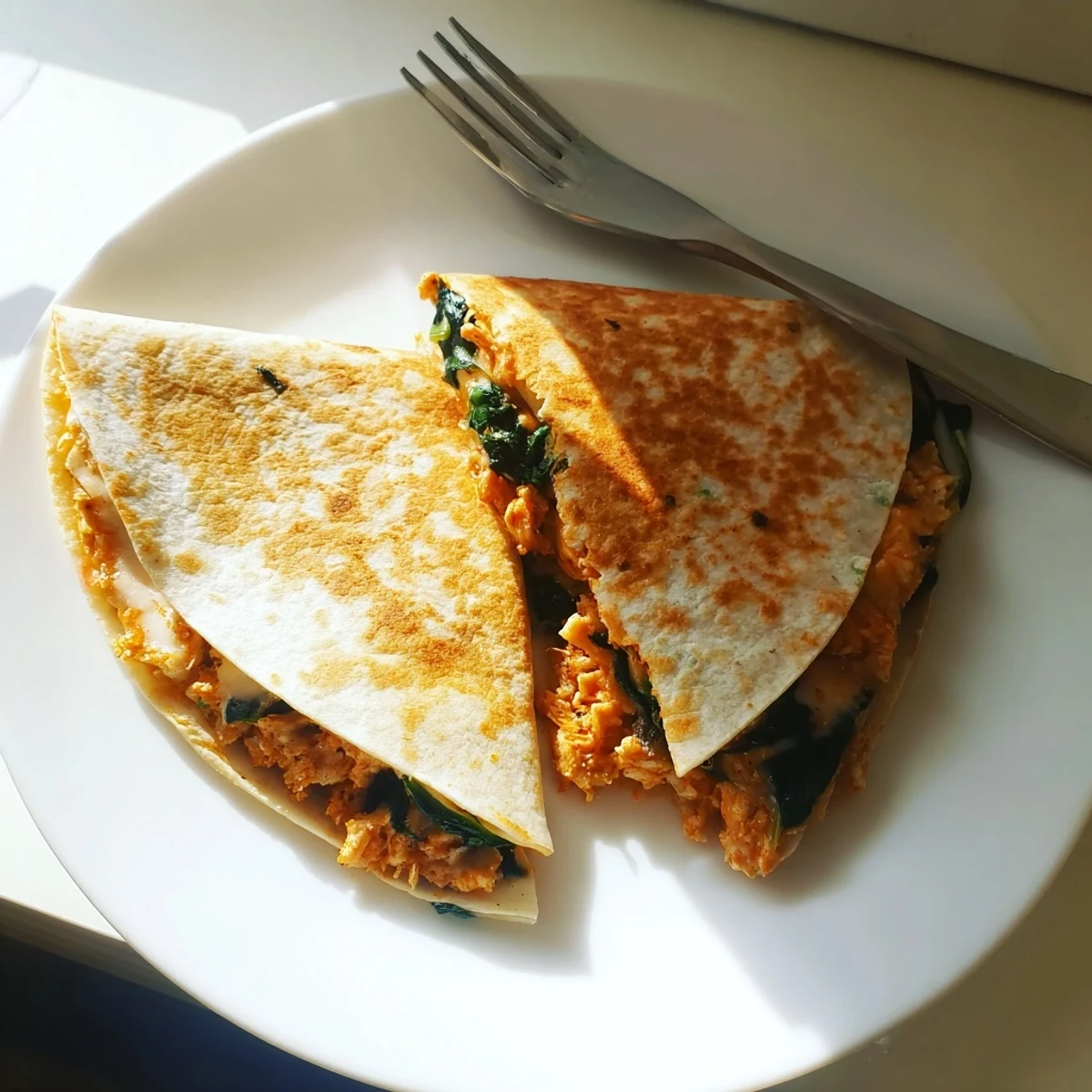 Close-up of a Chicken and Spinach Quesadilla slice revealing melted mozzarella, juicy chicken, and tender spinach filling.