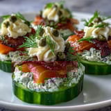Cucumber bites with cream cheese and smoked salmon, arranged on a platter with dill garnish for a fresh appetizer.