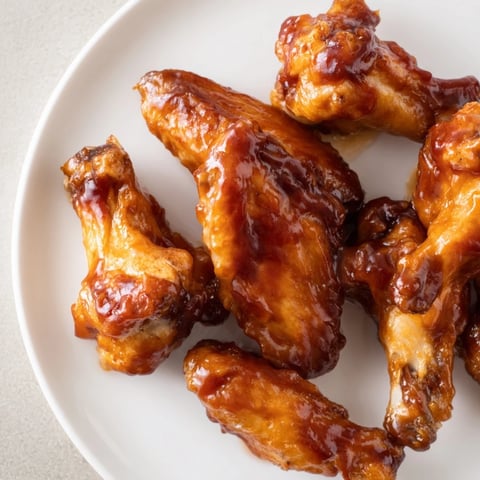 Crispy Baked Sticky Honey BBQ Wings glistening with a sweet, tangy glaze, perfect for sharing.