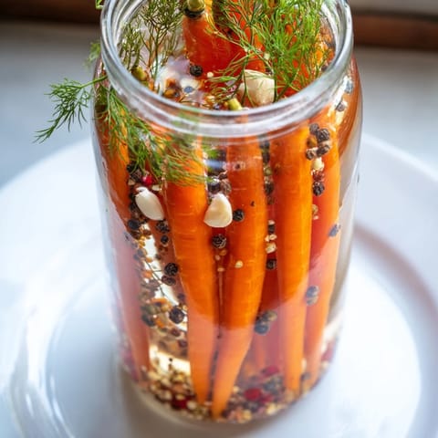 Close-up of Quick Pickled Carrot Spears with garlic and spices, capturing a tangy, flavorful appearance.
