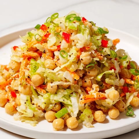 Enjoy a refreshing scoop of fiber-forward chickpea salad, boasting colorful veggies and a zesty taste.