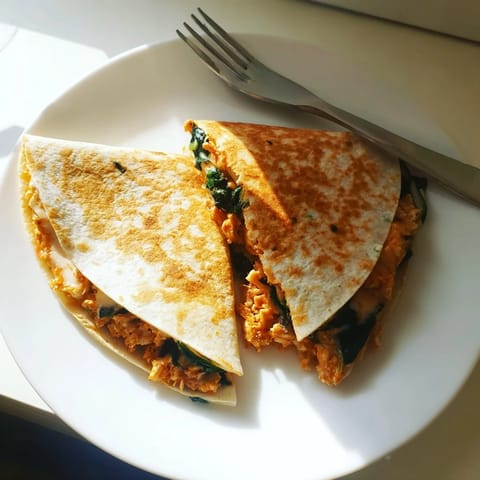 Close-up of a Chicken and Spinach Quesadilla slice revealing melted mozzarella, juicy chicken, and tender spinach filling.
