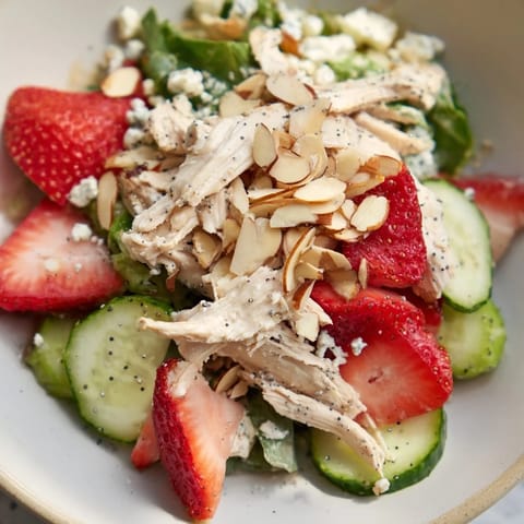 Colorful Strawberry Poppy Seed Chicken Salad served over mixed greens with toasted almonds and optional feta.  