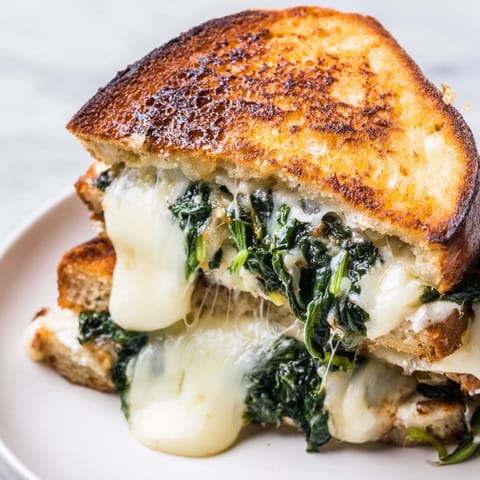 Warm, savory Feta & Spinach Stuffed Grilled Cheese on a rustic plate, ready to be dipped in tomato soup.